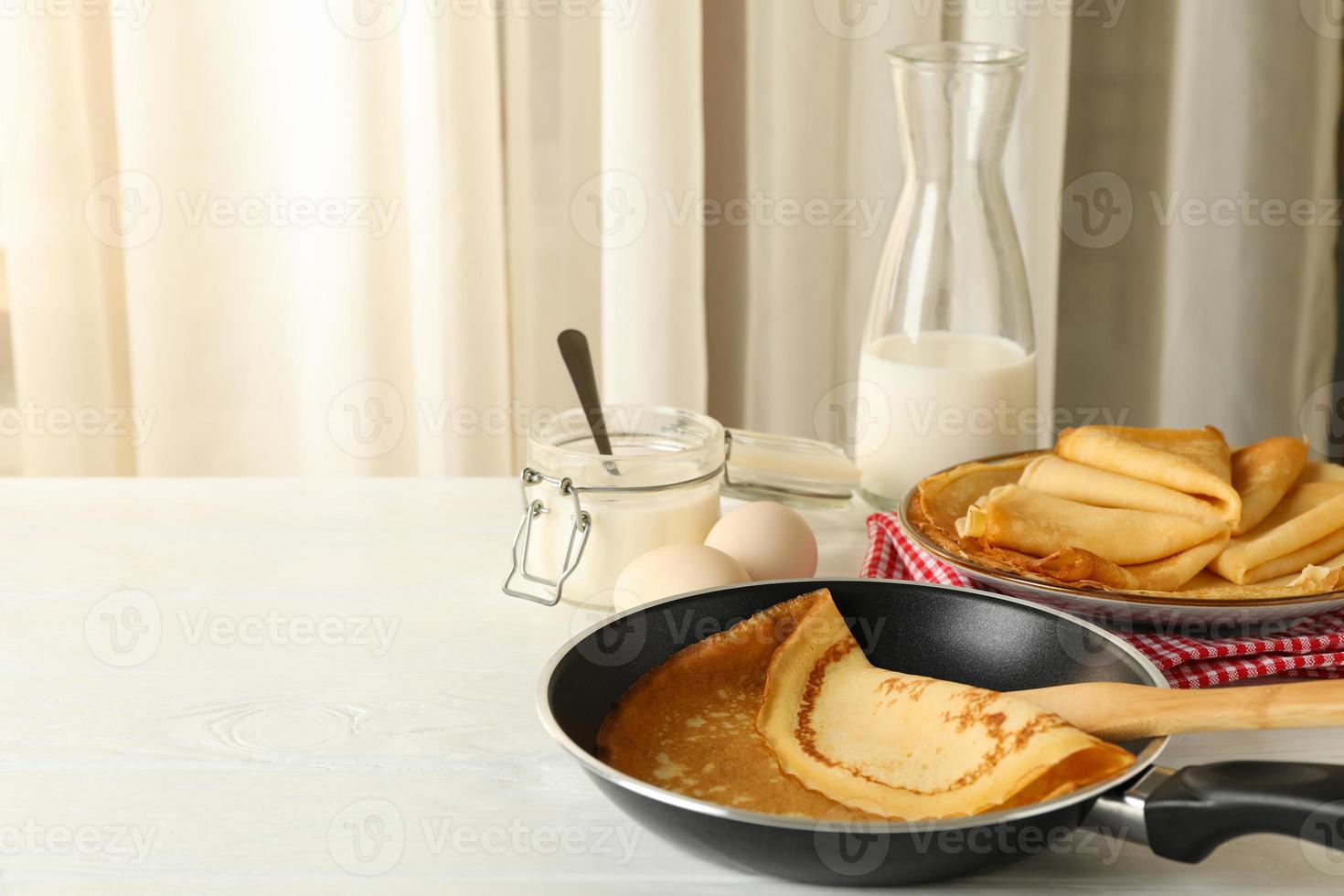 Concepto de delicioso desayuno con tortitas finas sobre mesa de madera blanca foto