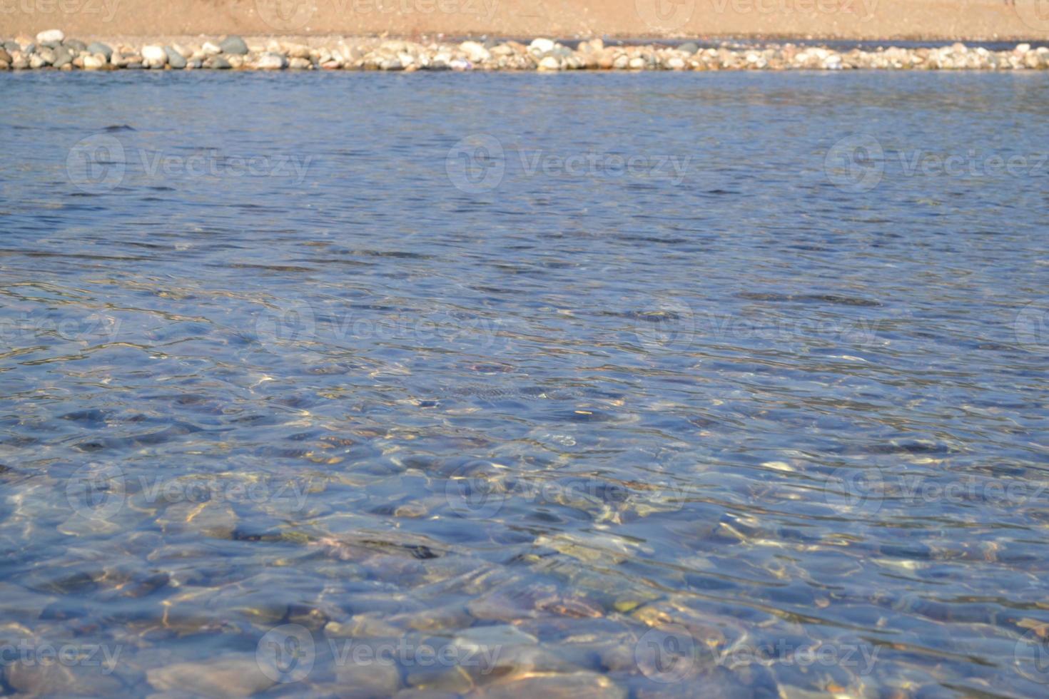 Colored pebbles under water at the coast Close-up. Stones under water. Background. photo