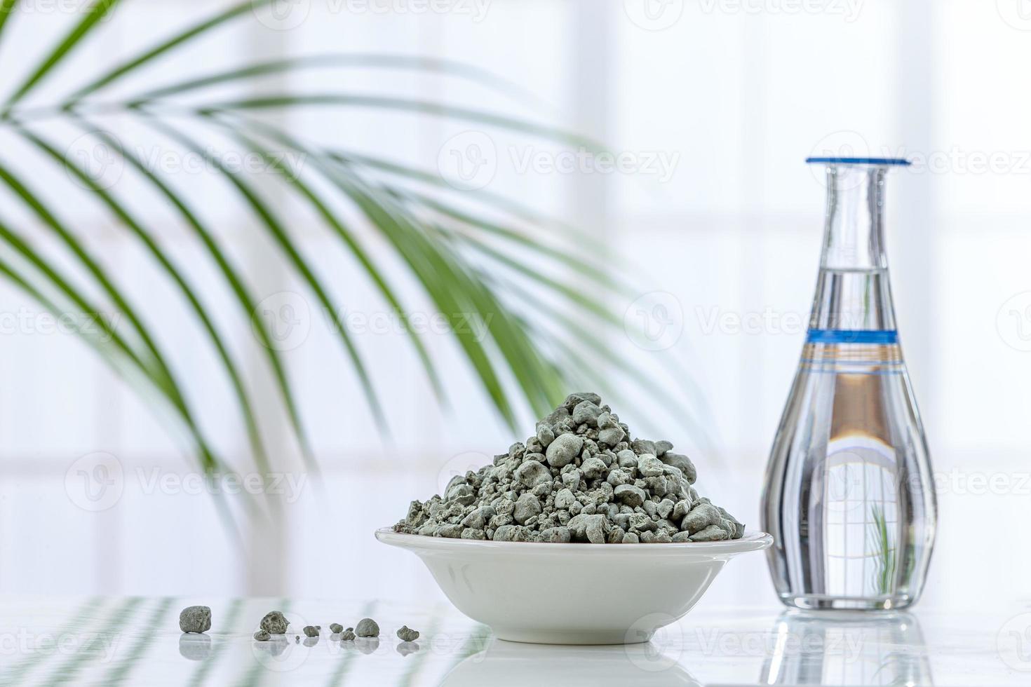 Polvo de arcilla verde seca y mascarilla para el rostro y el cuerpo en un recipiente de cerámica aislado en blanco foto