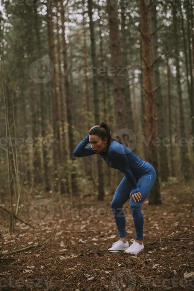 Young woman take a break during outdoor exercise on the forest trail at autumn photo