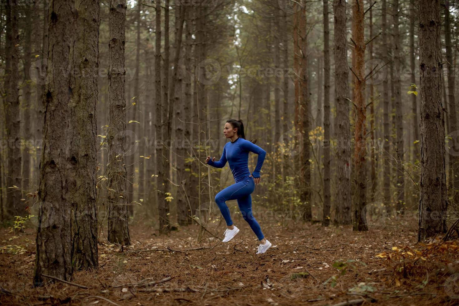 Young woman running on the forest trail at autumn photo