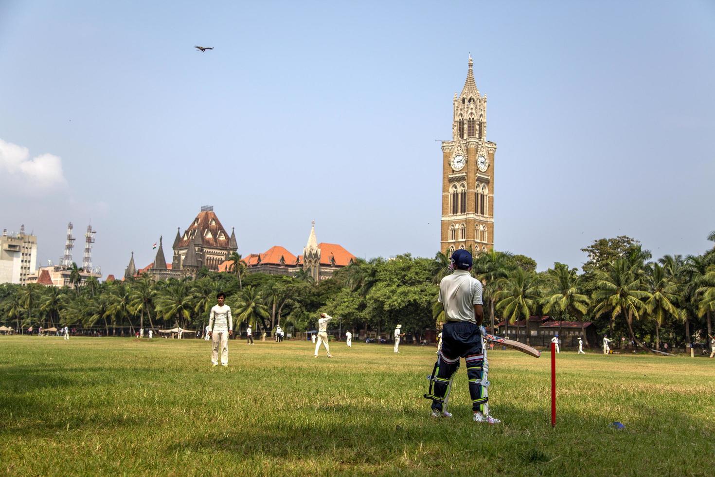 Mumbai, India, 2015 - Personas no identificadas jugando sqiash junto a la torre del reloj de Rajabai en Mumbai. La torre se completó en 1878 y tiene una altura de 85 m. foto