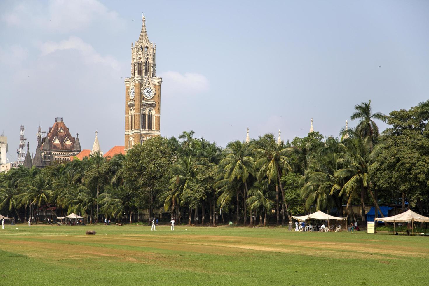 mumbai, india, 2015 - desconocidos jugando sqiash junto a la torre del reloj rajabai en mumbai. La torre se completó en 1878 y tiene una altura de 85 m. foto