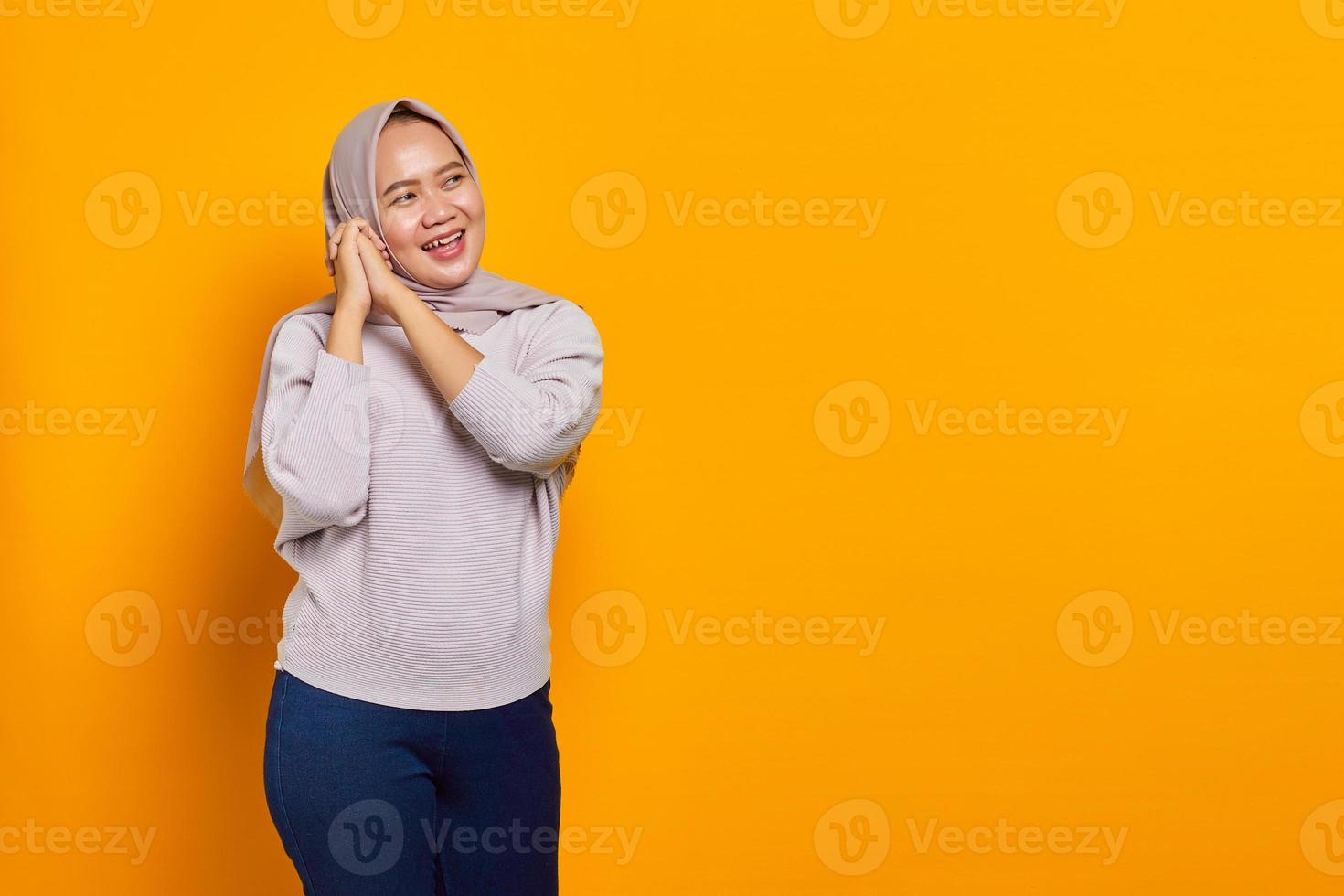 Feliz joven asiática frotar las manos y esperar disfrutar sobre fondo amarillo foto