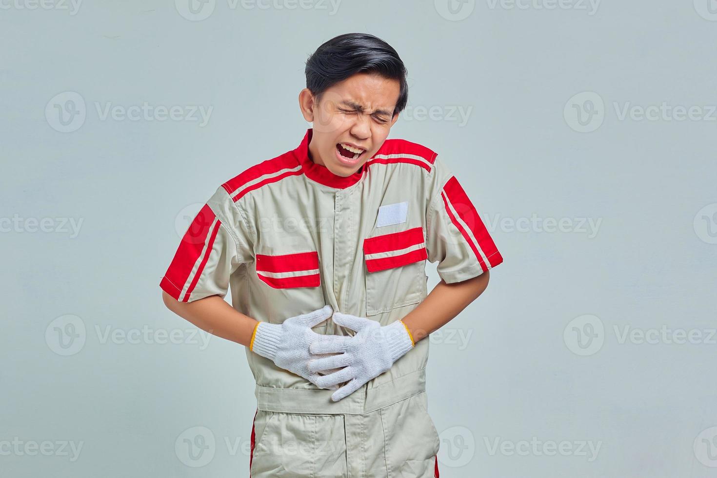 Portrait of handsome man wearing mechanic uniform loughing hard out loud because funny crazy joke with hands on body photo