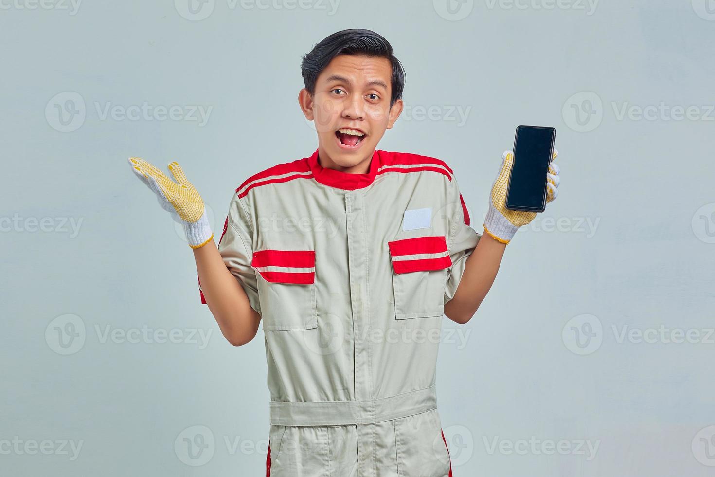 Portrait of handsome man wearing mechanic uniform and celebrating success on gray background photo