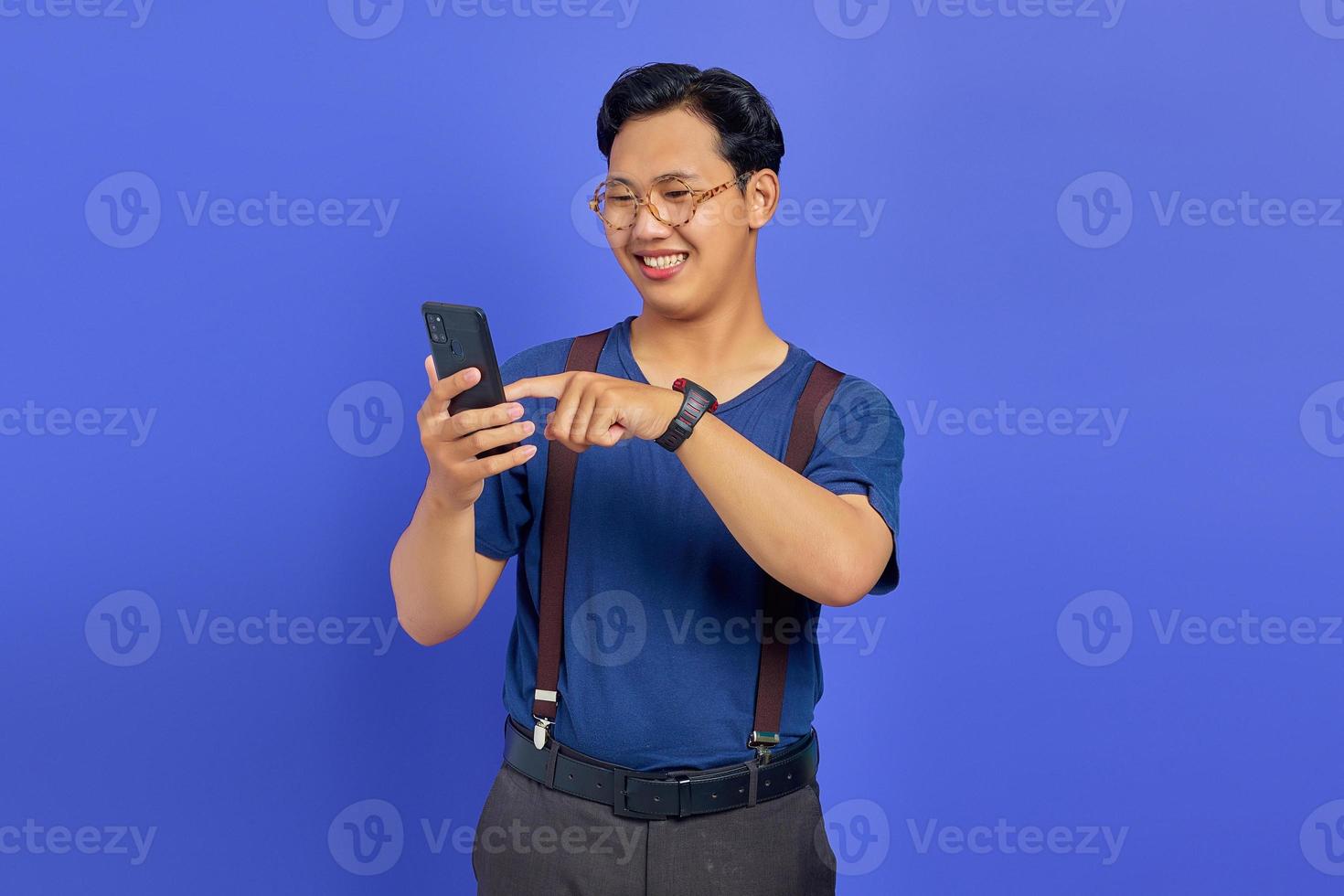 Smiling man using mobile phone to browse with empty space over purple background photo