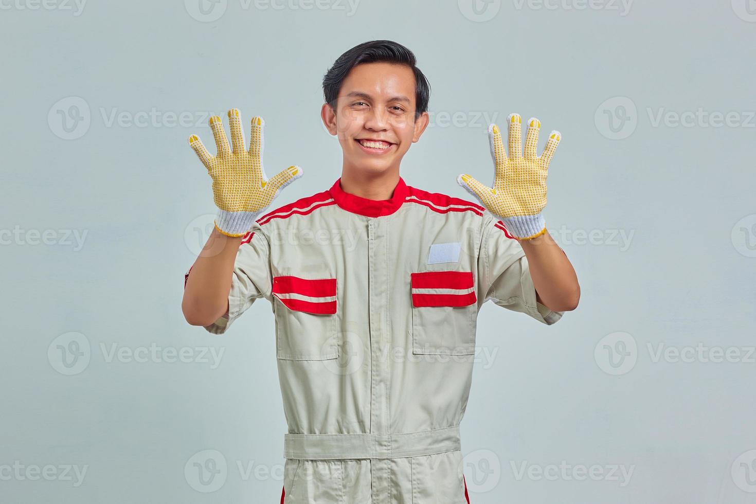 Portrait of cheerful handsome man wearing mechanical uniform showing palms over gray background photo