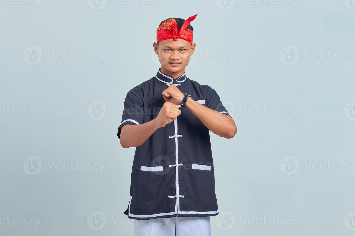 Retrato de joven deportista con kimono practicando karate con gesto de puño cerrado aislado sobre fondo gris. foto