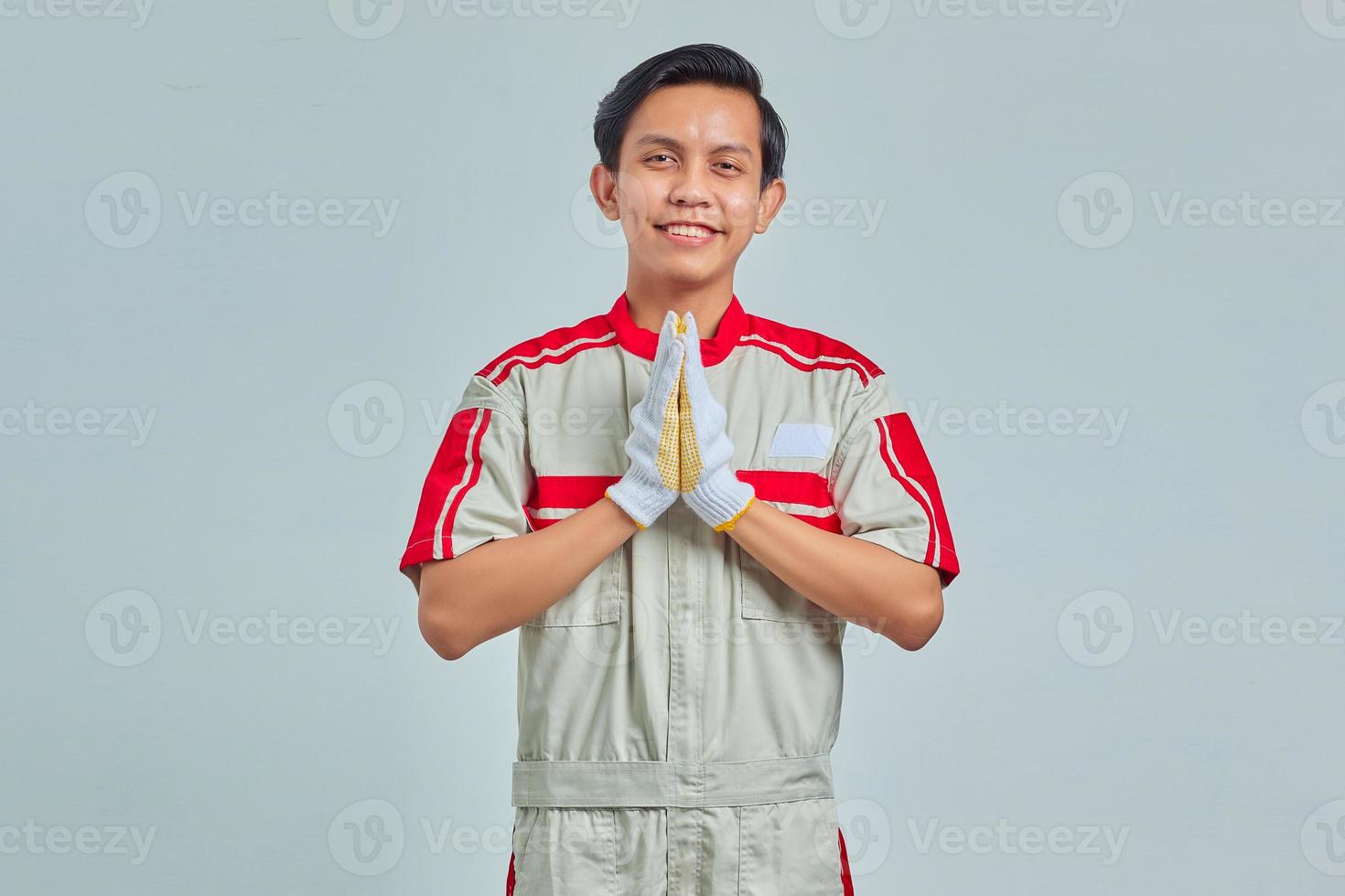 Portrait of young mechanic man greeting with big smile on his face isolated on gray background photo