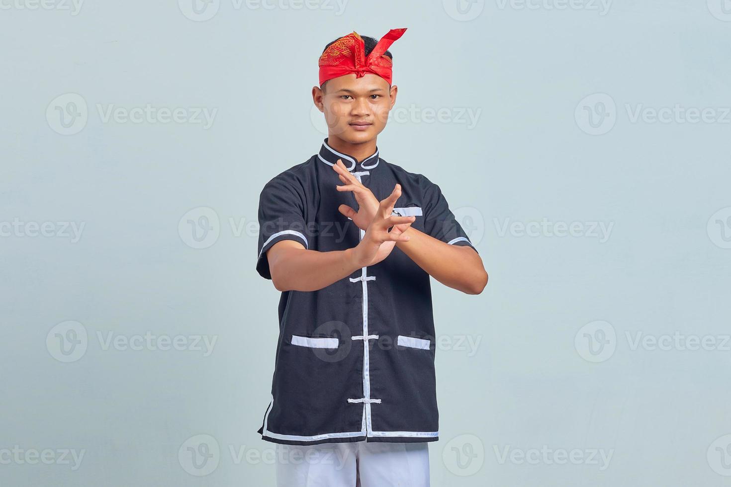 Photo of handsome young sportsman  dressed in kimono practice in karate isolated over grey background