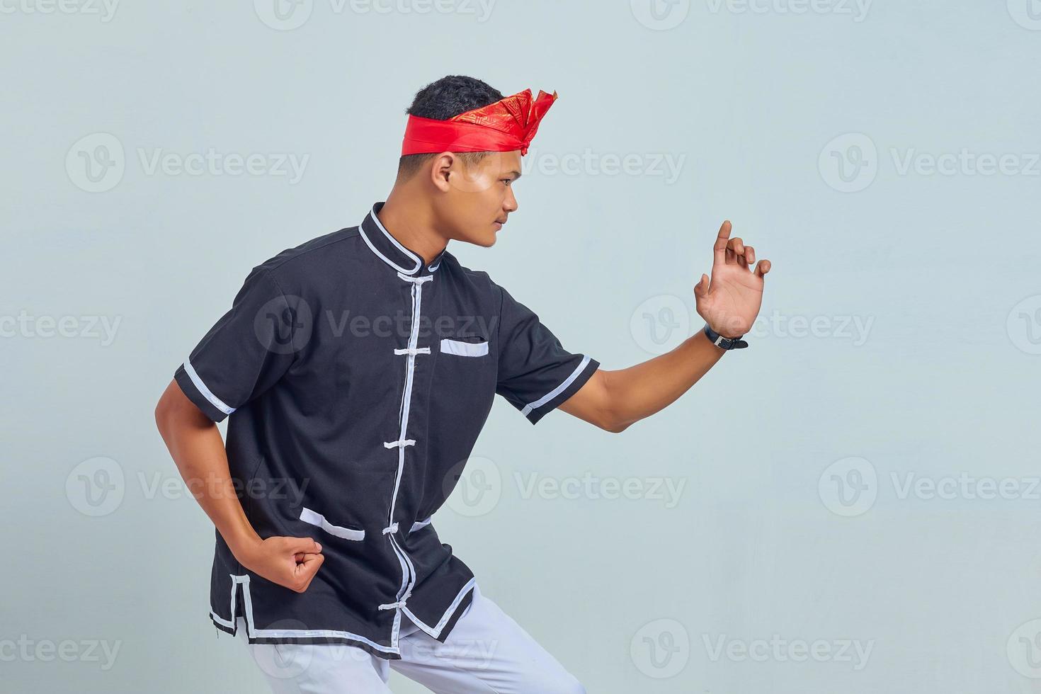 Portrait of handsome asian sportsman wearing kimono practicing karate isolated over gray background photo