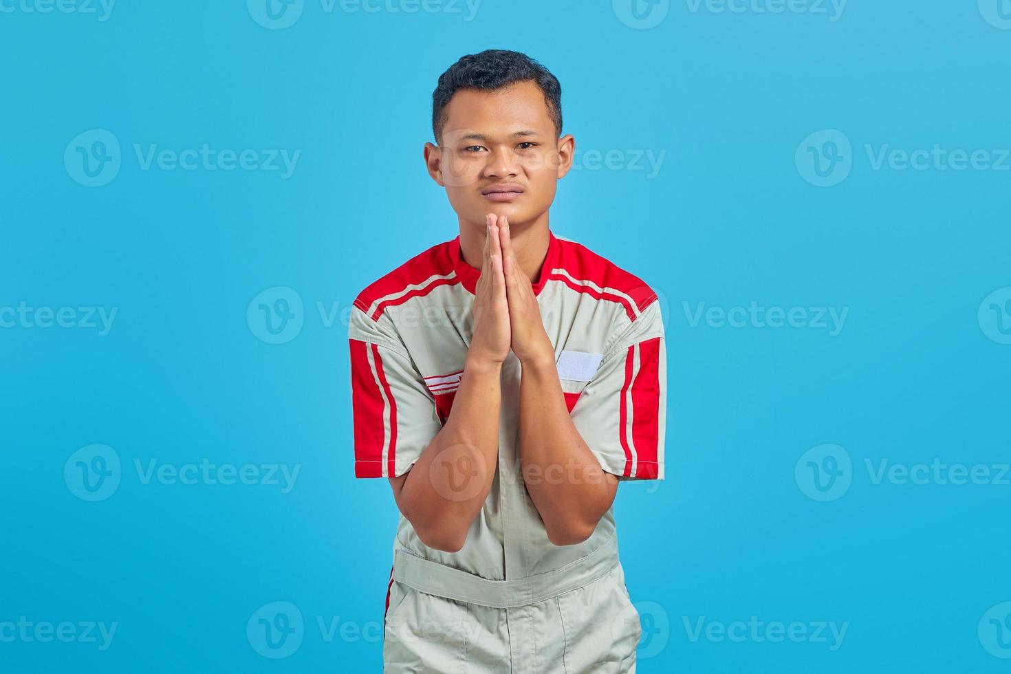 Mechanic man wearing uniform praying with hands together asking for forgiveness smiling confidently photo