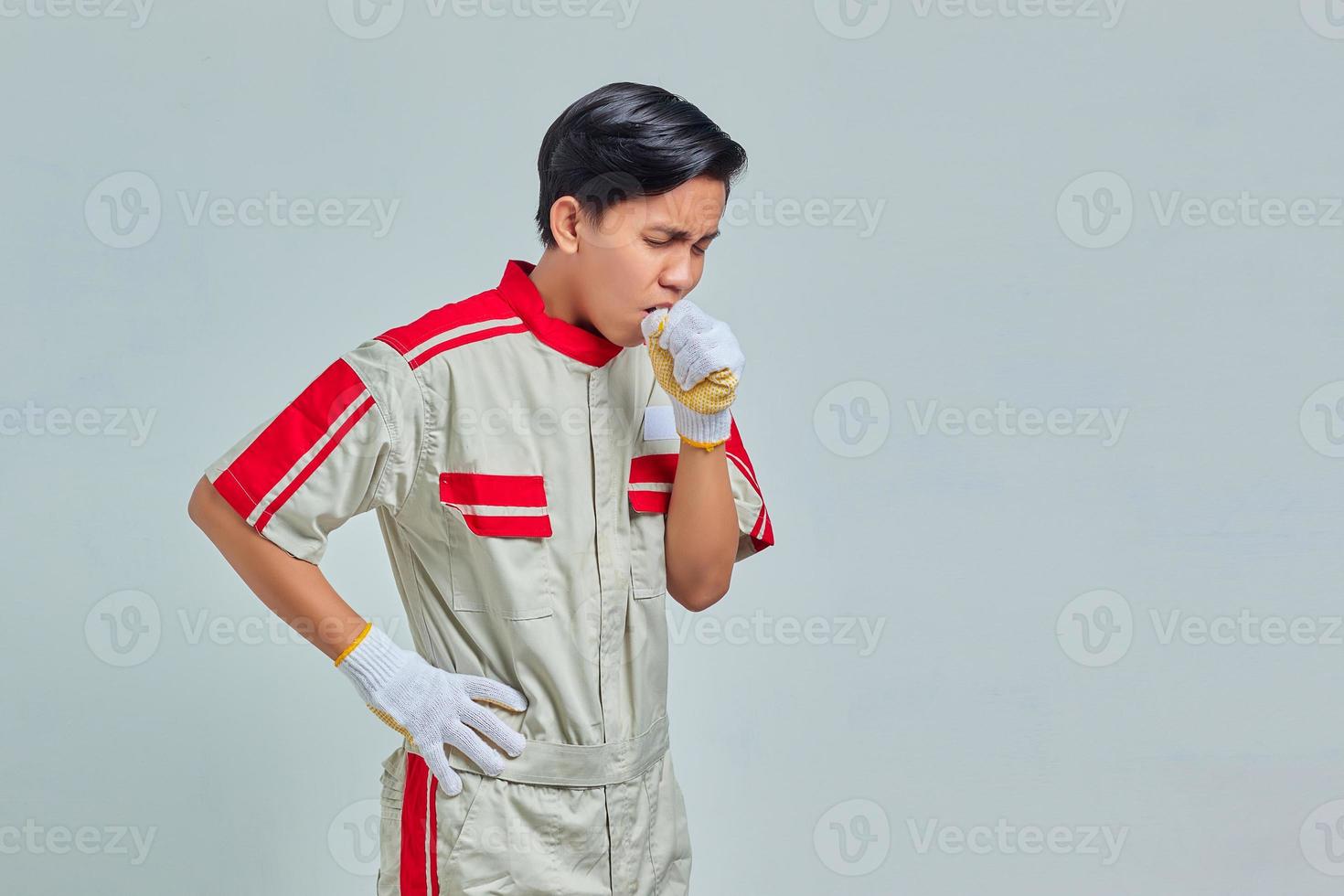 Handsome man wearing mechanic uniform feeling unwell and coughing are symptoms of cold or bronchitis photo