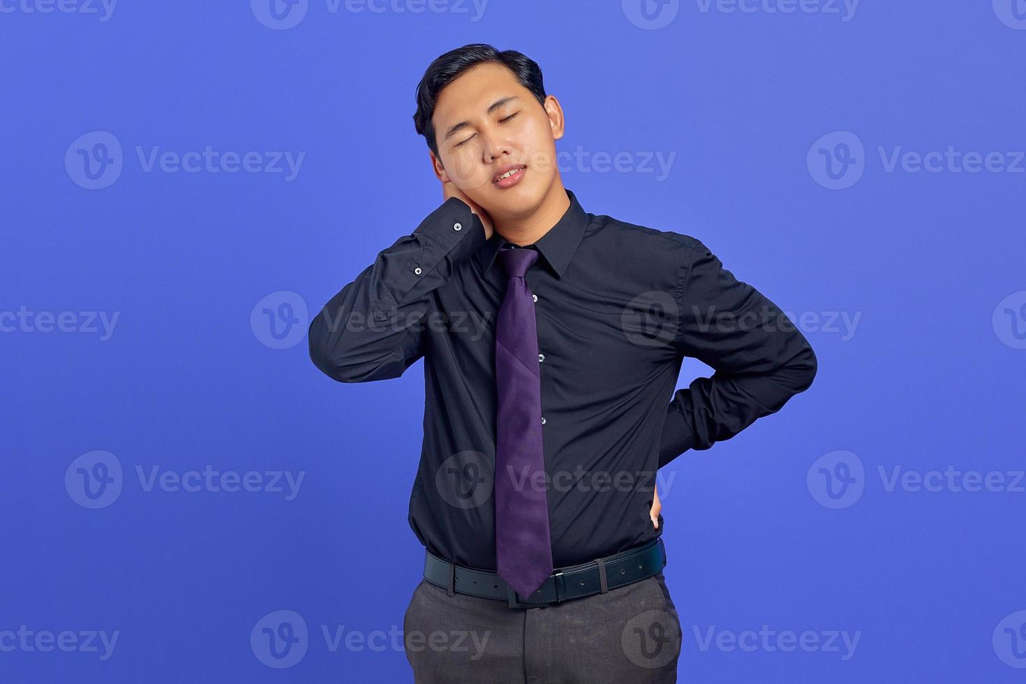 Handsome young businessman feeling tired after a long day working on purple background photo