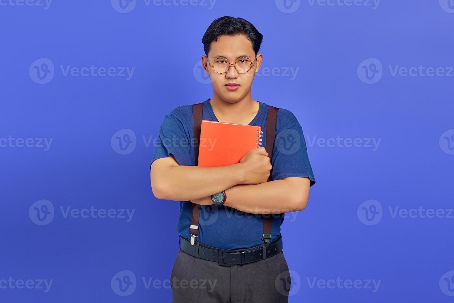 Happines Young man holding notebook tightly and looking ahead on purple background photo