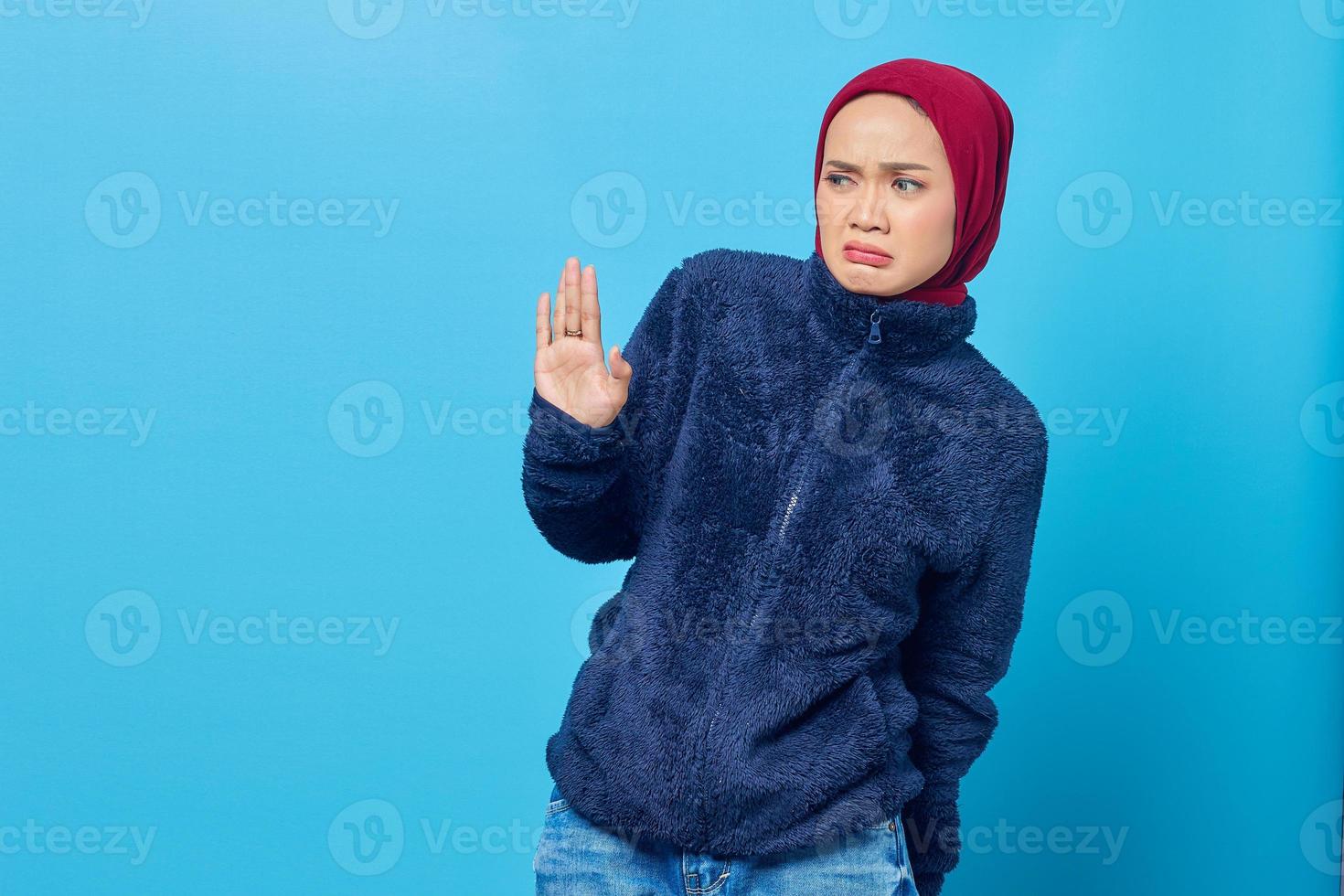 Retrato de hermosa mujer asiática tira de la mano a un lado en gesto de parada sobre fondo azul. foto