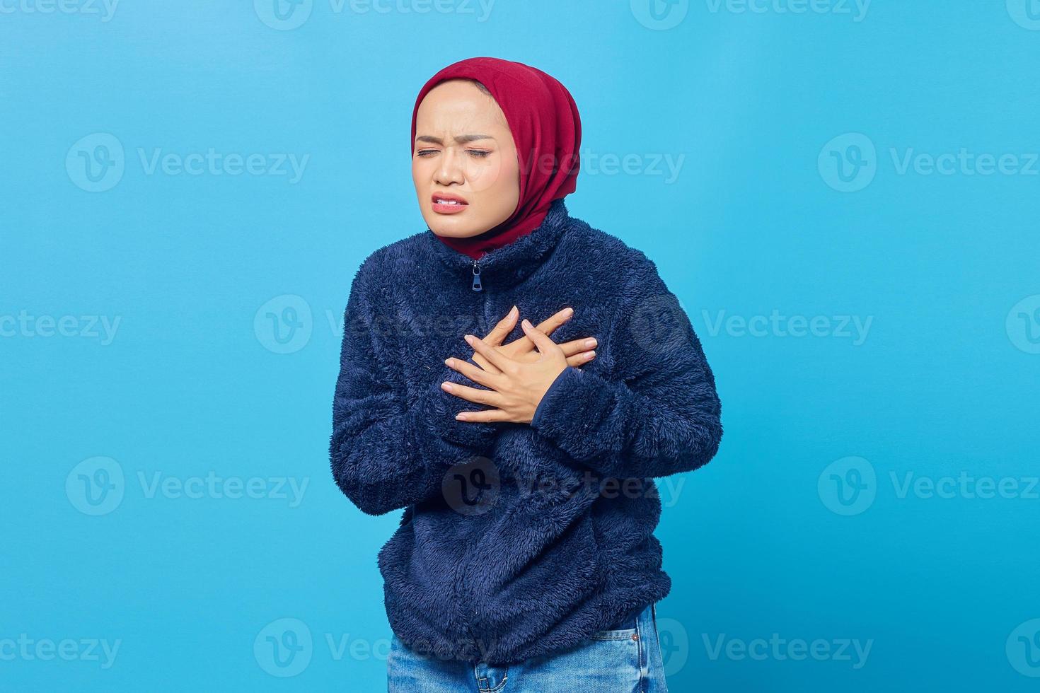 Retrato de una joven mujer asiática con dificultad para respirar y manteniendo ambas palmas sobre el pecho foto