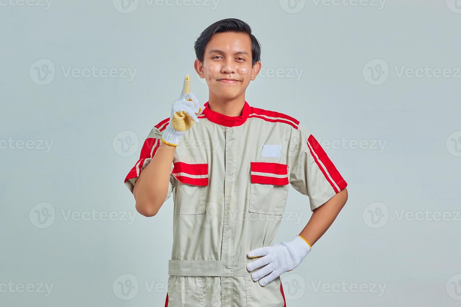 Portrait of excited handsome man wearing mechanical uniform having creative idea and looking at camera over gray background photo