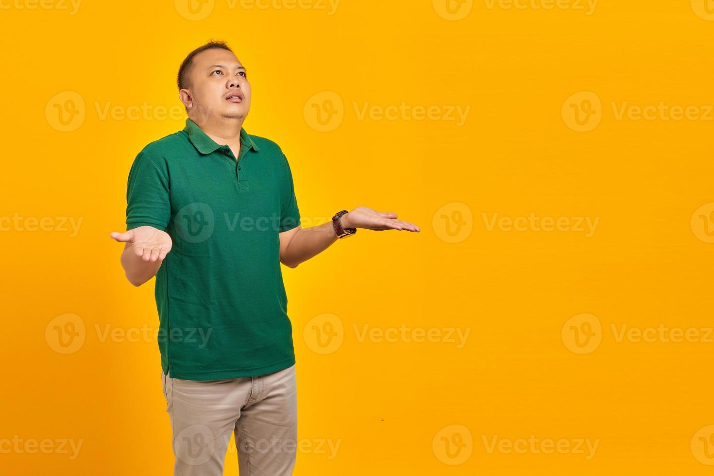 Portrait of asian man surprised with confused and displeased expression on yellow background photo