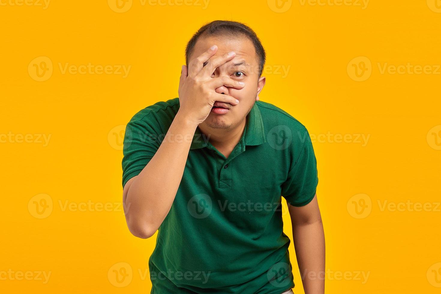 Portrait of surprised young Asian man with hidden palm visible about his mistake over yellow background photo