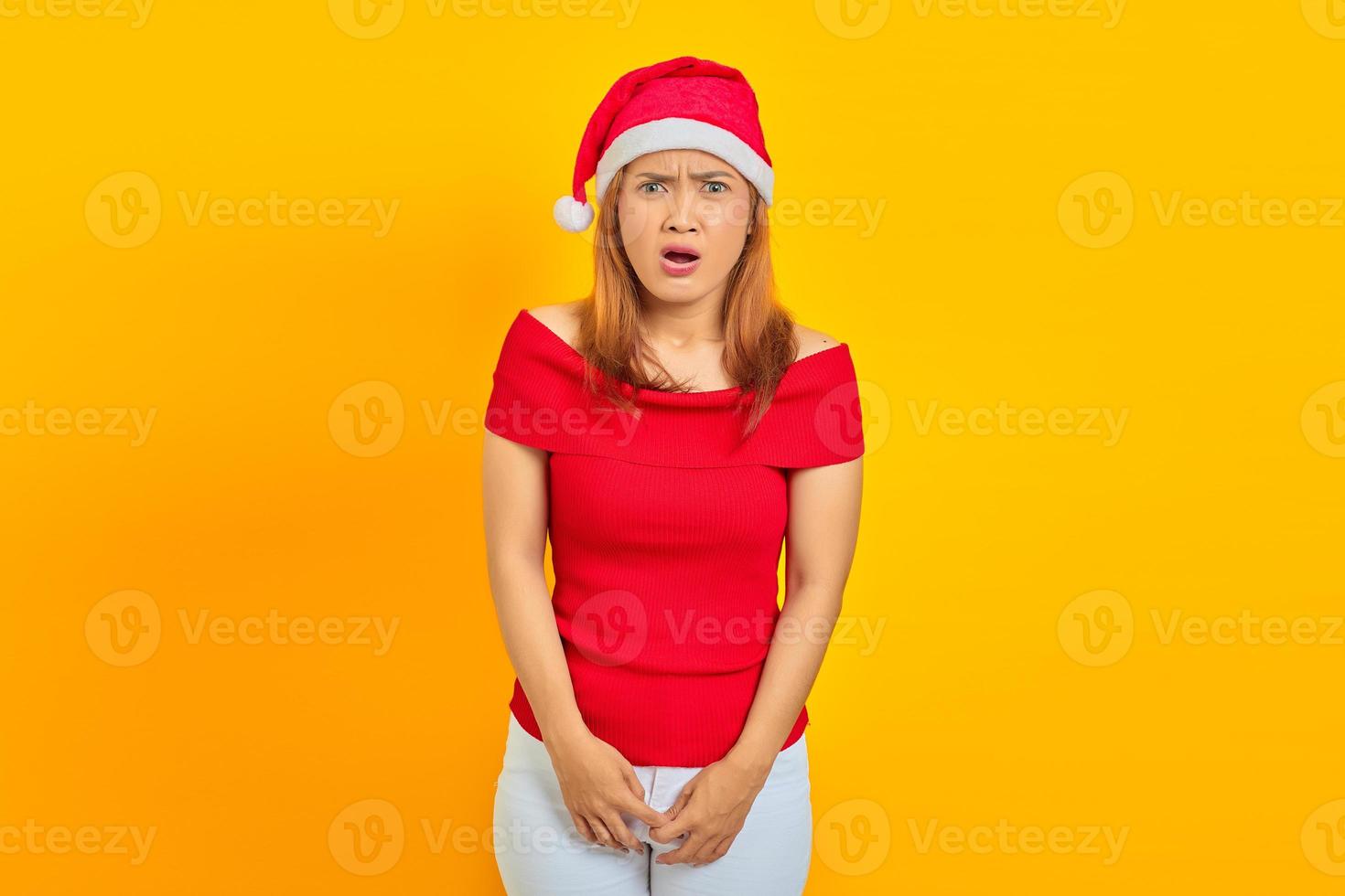 retrato, de, sorprendido, joven, mujer asiática, con, boca abierta, y, llevando, sombrero de navidad, en, fondo amarillo foto