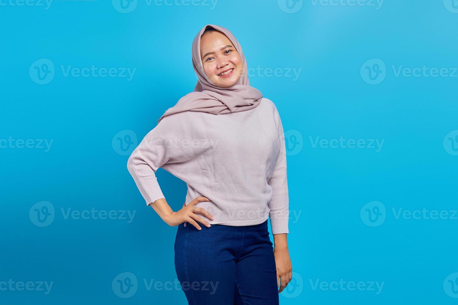 Cheerful Asian woman looking at camera over blue background photo