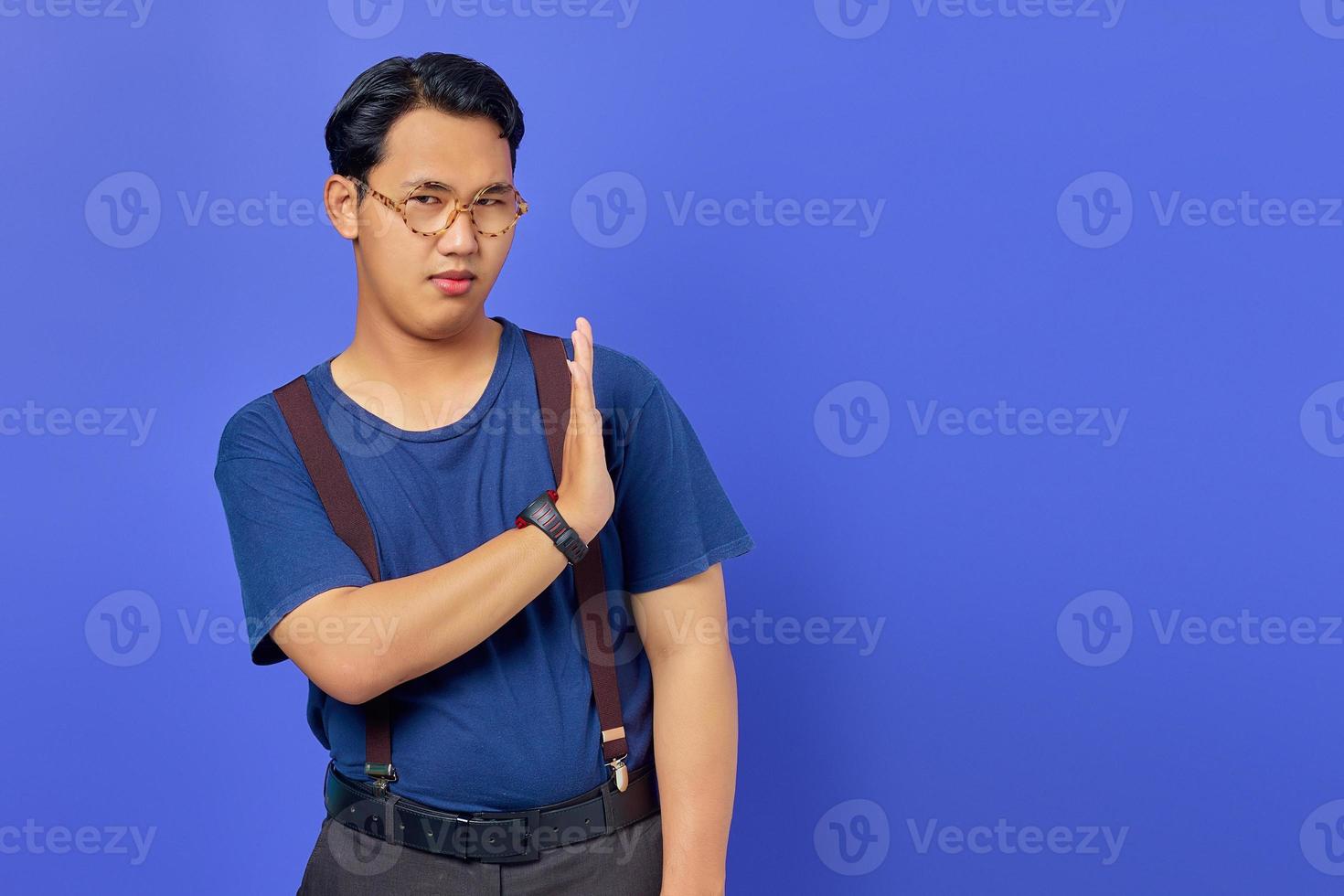 Portrait of nervous anxious young Asian man make stop don't move gesture over purple uebackground photo