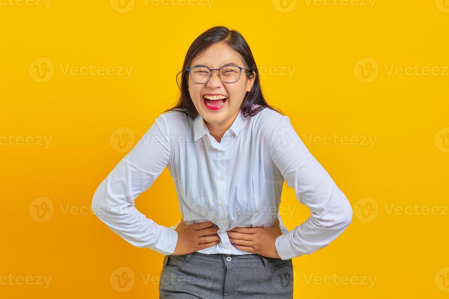 Portrait of young business woman laughing heartily at funny crazy joke with hands on body photo