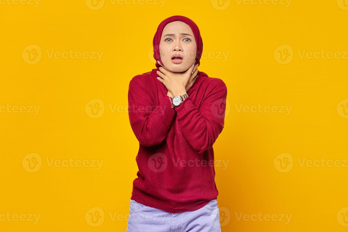 Retrato de joven mujer asiática sofocar porque doloroso estrangulamiento sobre fondo amarillo foto