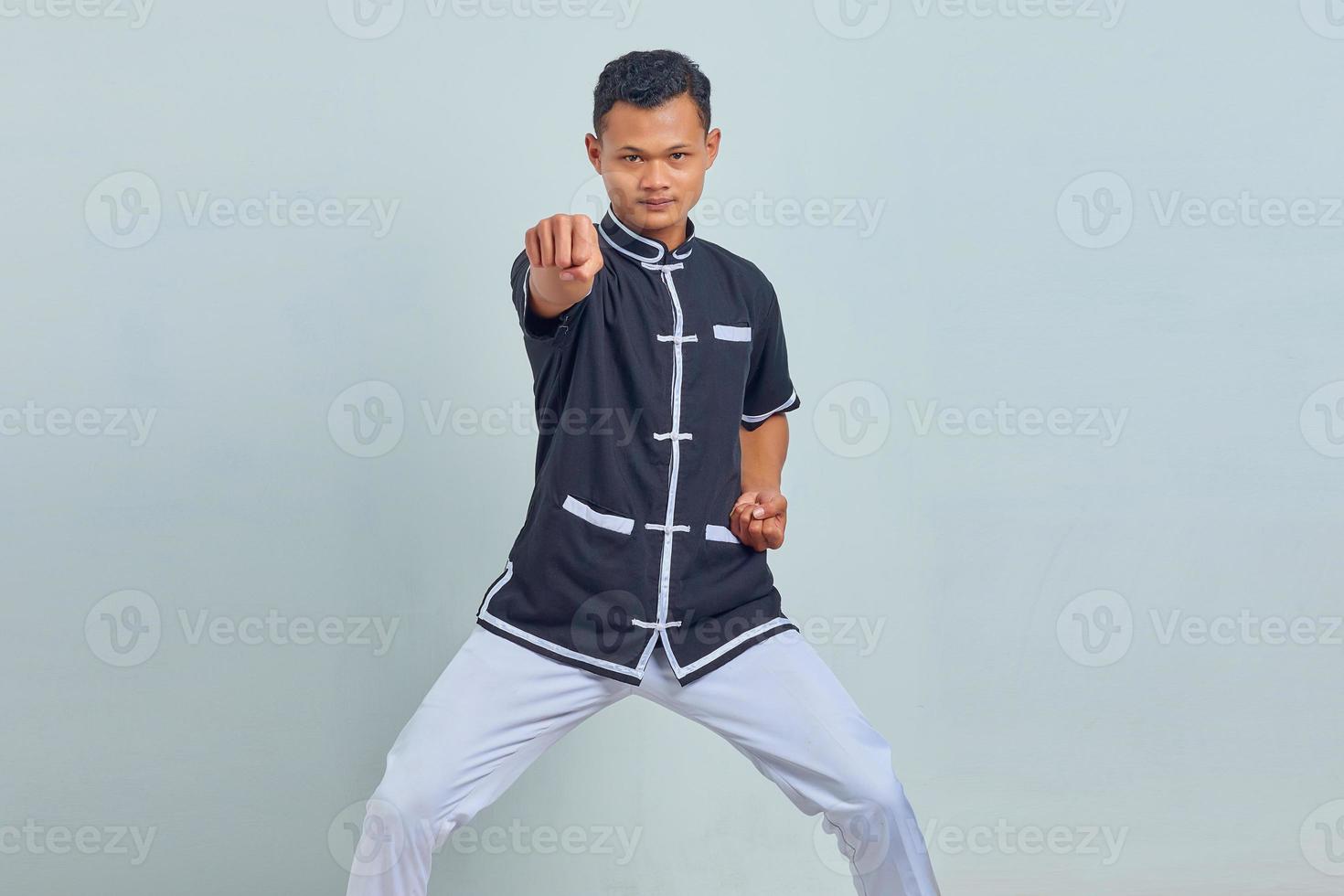 Portrait of handsome asian sportsman wearing kimono practicing karate isolated over gray background photo