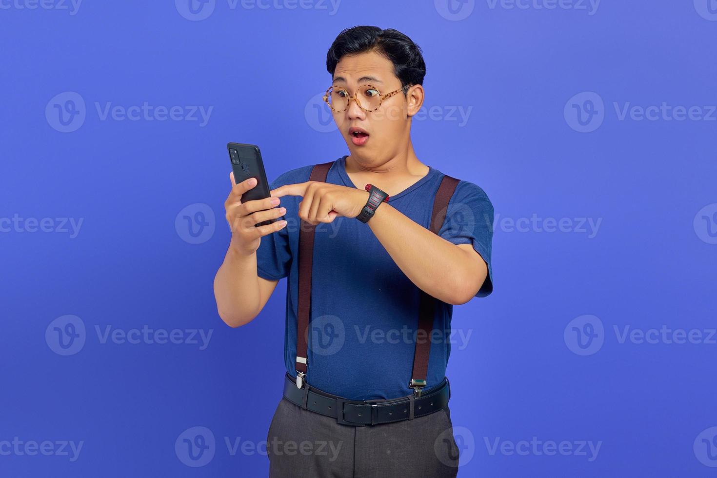 Shocked young man opening social media on smartphone on purple background photo