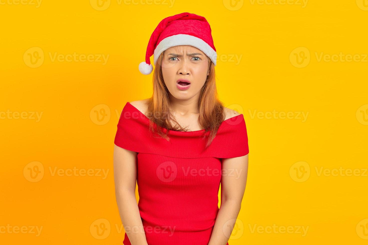 retrato, de, sorprendido, joven, mujer asiática, con, boca abierta, y, llevando, sombrero de navidad, en, fondo amarillo foto