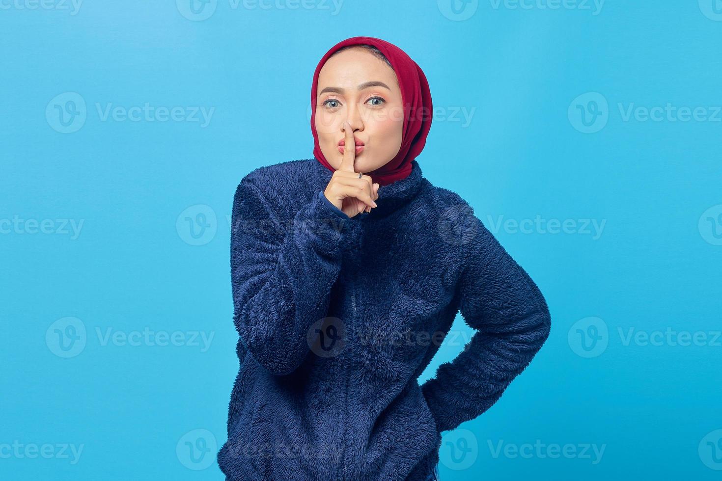 Hermosa mujer asiática haciendo el dedo en los labios boca silencioso gesto silencioso sobre fondo azul. foto