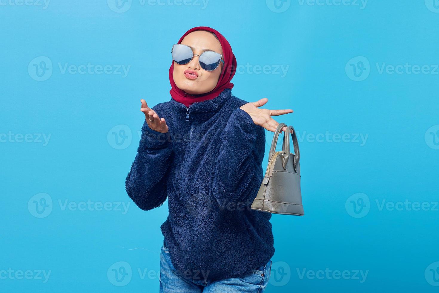 Hermosa joven asiática sosteniendo la bolsa con expresión alegre y enviando beso al aire foto