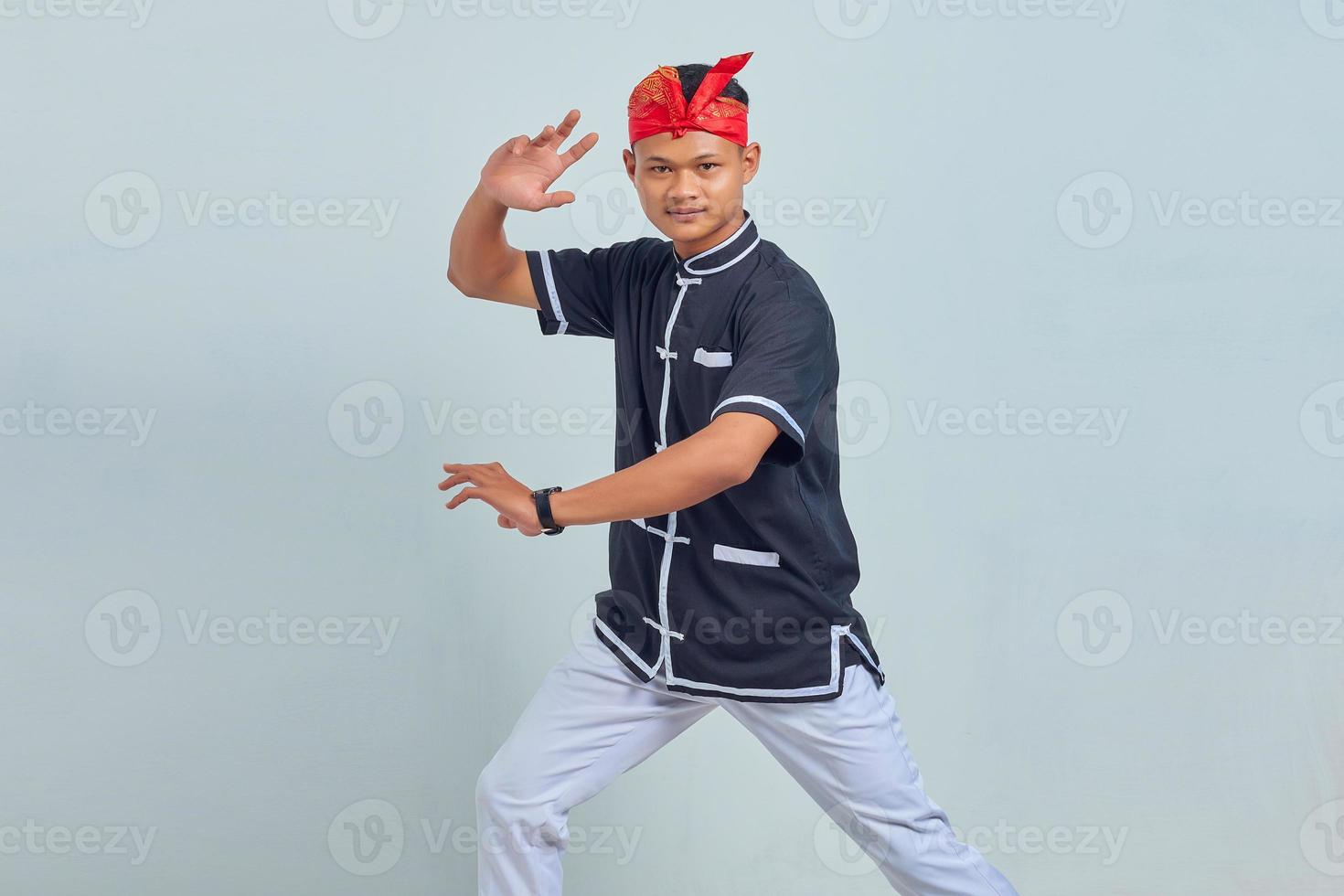 Photo of handsome young sportsman  dressed in kimono practice in karate isolated over grey background