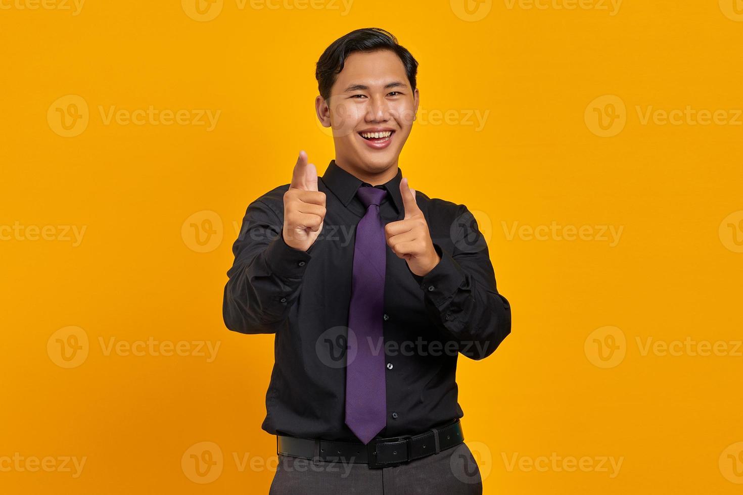 Cheerful handsome young businessman pointing at camera on yellow background photo