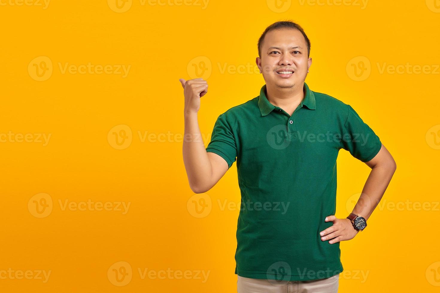 Smiling handsome young man pointing to copy room on yellow background photo