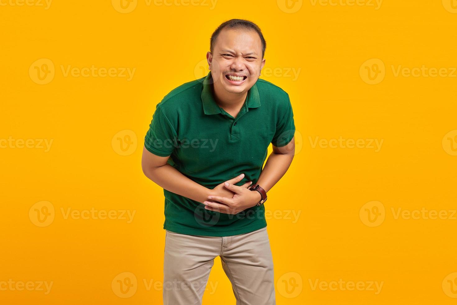 Attractive asian young man laughing out loud at funny on yellow background photo
