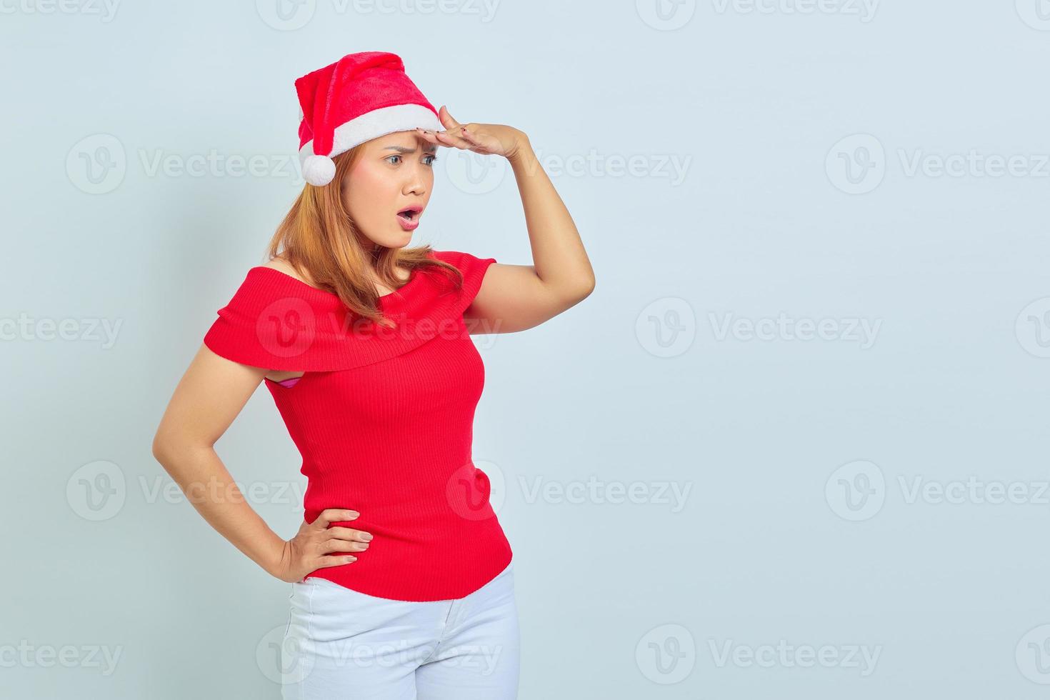 Photo of beautiful Asian girl in christmas hat with surprise fasial expression and open mouth on white background