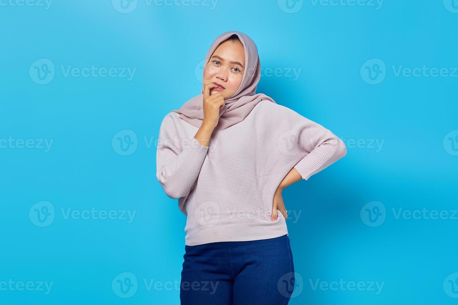 Portrait of smiling young asian woman thinking about question with finger hand on chin photo