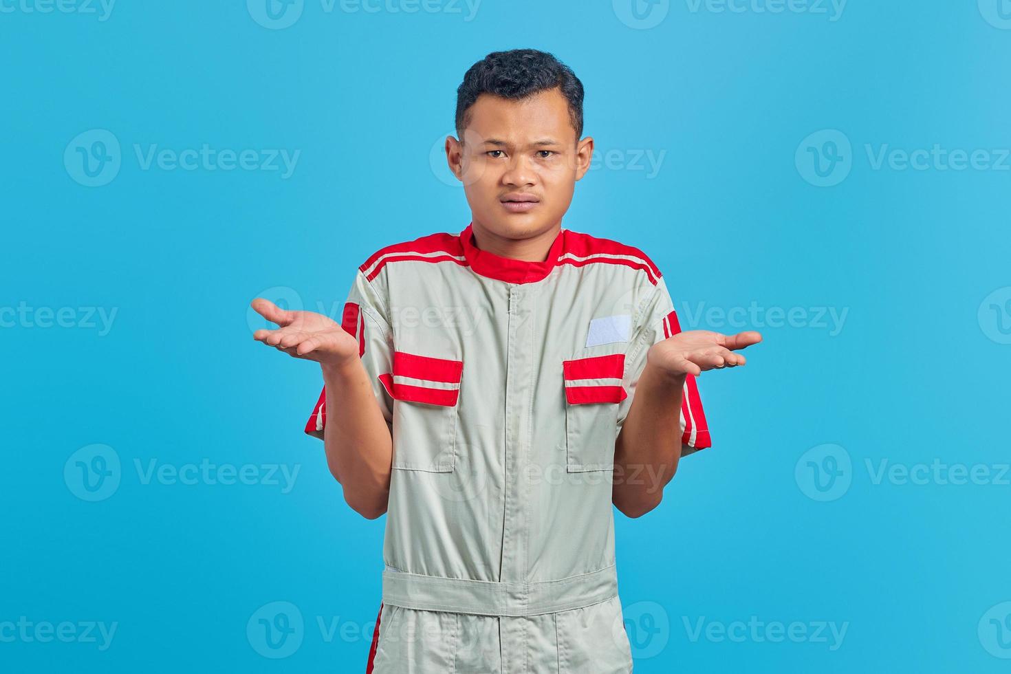 Shocked asian mechanic portrait with confused and displeased expression on yellow background photo