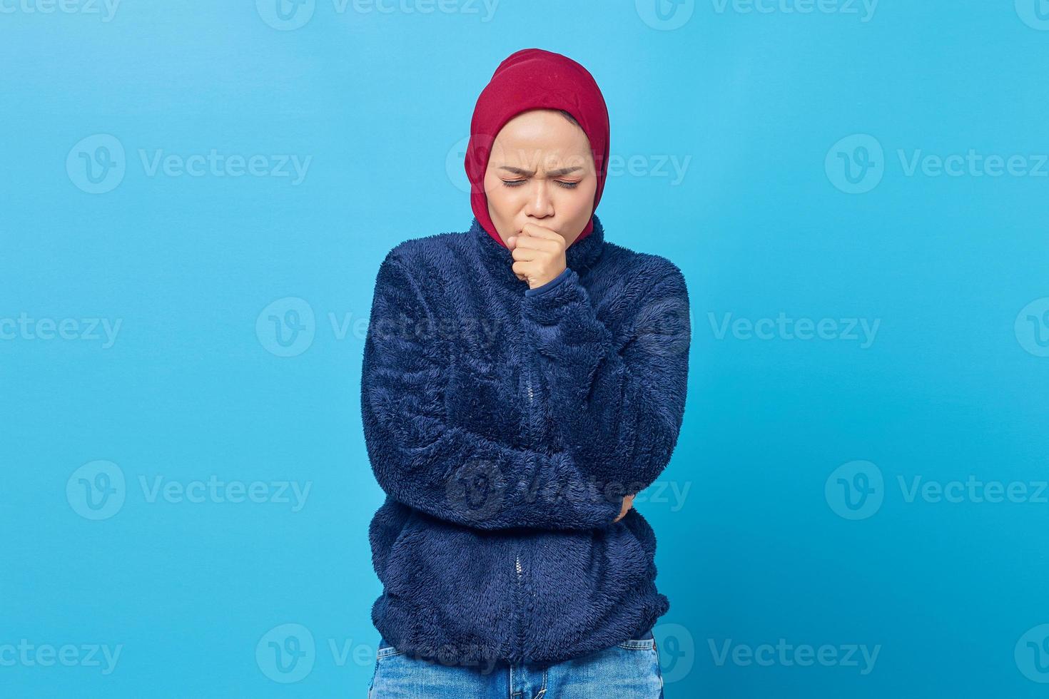 Portrait of beautiful Asian woman feeling unwell and coughing on blue background photo