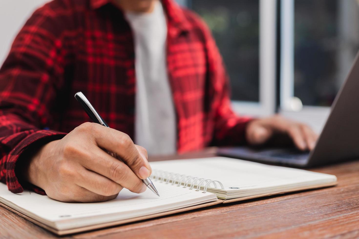 man holding a pen sitting on a desk writing photo