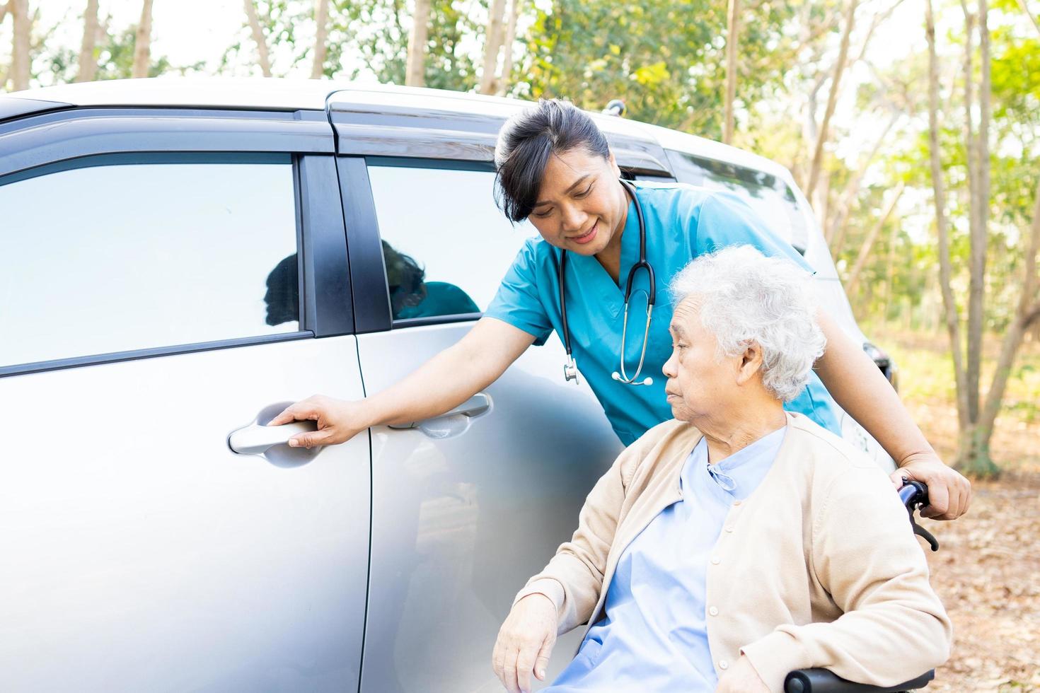 Help and support asian senior or elderly old lady woman patient sitting on wheelchair prepare get to her car, healthy strong medical concept. photo