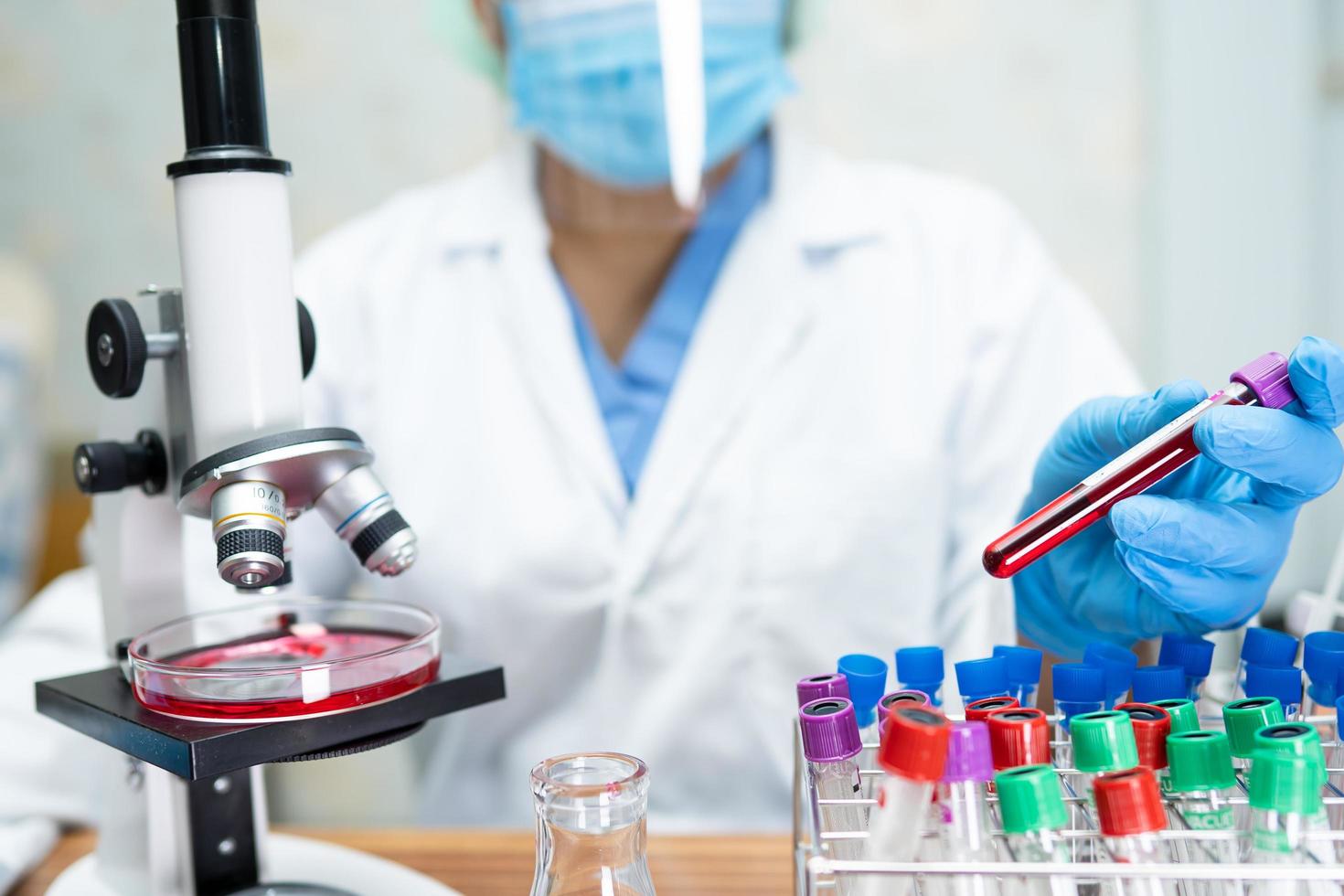 Asian scientist biochemist or microbiologist working research with a microscope in laboratory. For protect outbreak Coronavirus Covid19, bacteria and germs. photo