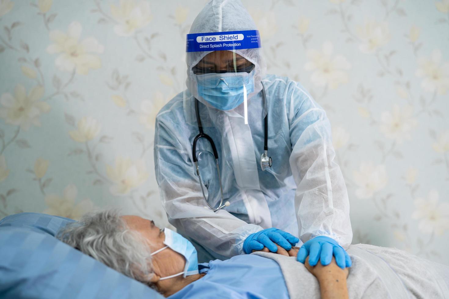 Asian doctor wearing face shield and PPE suit new normal to check patient protect safety infection Covid-19 Coronavirus outbreak at quarantine nursing hospital ward. photo