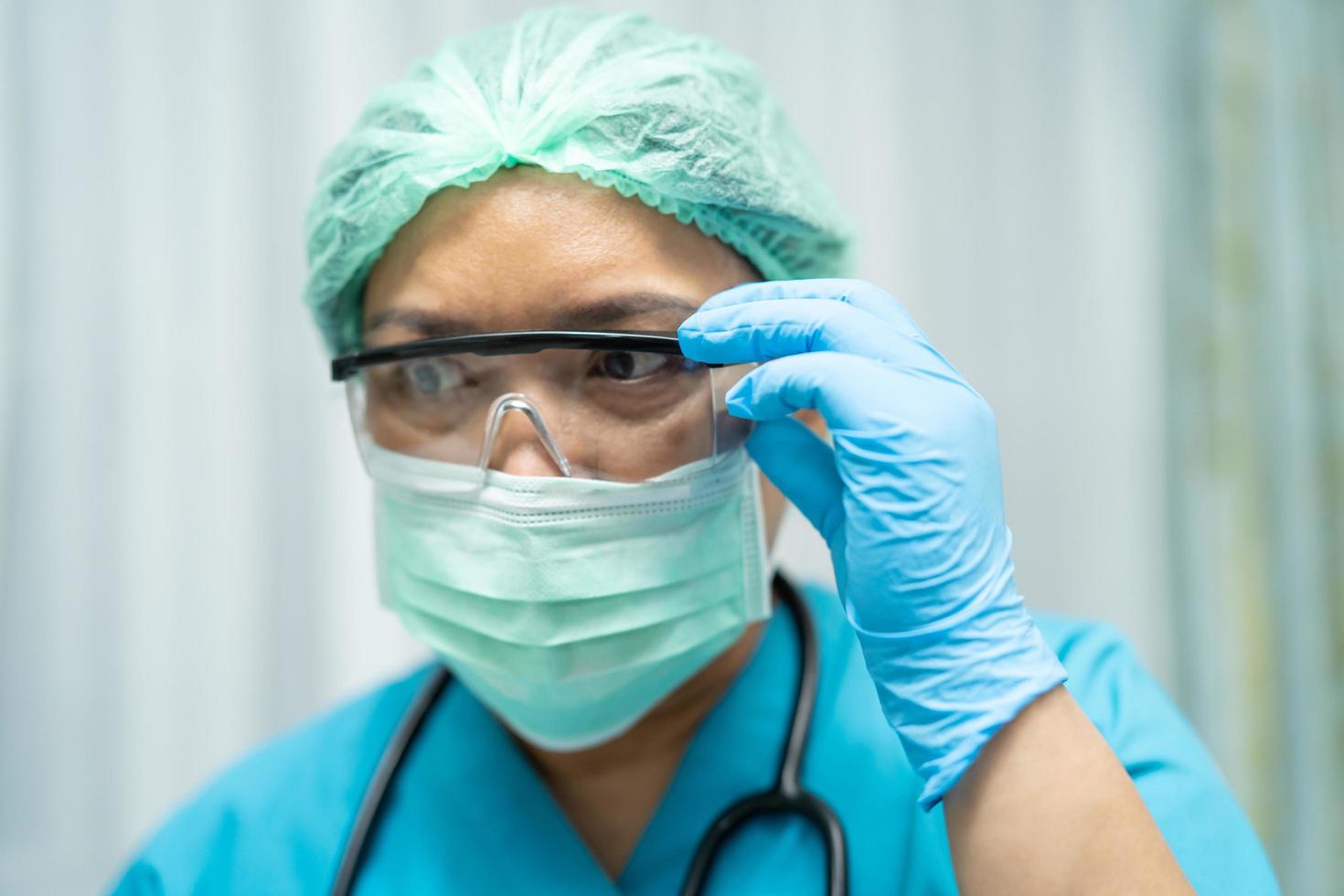 Asian doctor wearing face shield and PPE suit new normal to check patient protect safety infection Covid-19 Coronavirus outbreak at quarantine nursing hospital ward. photo
