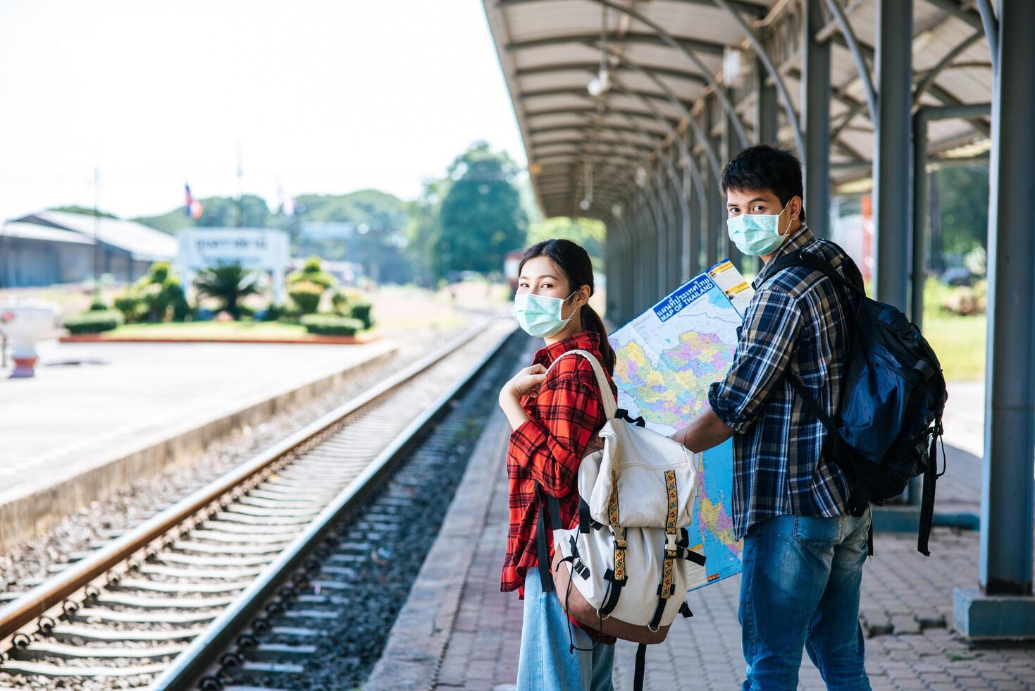 Both male and female tourists look at the map beside the railway. photo