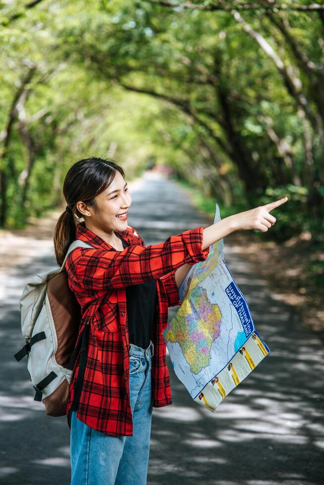 Female tourists stand and look at the map on the road. photo
